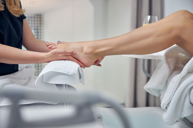 Primo piano del piede della donna che viene trattato con le mani di un professionista di bellezza dopo le procedure igieniche