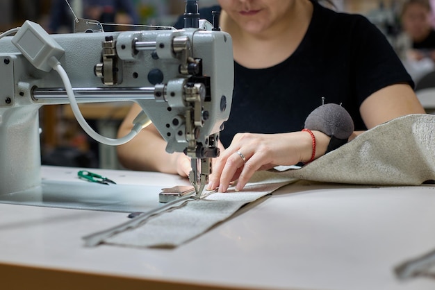 Primo piano del processo di cucitura del tessuto da parte di una donna in produzione