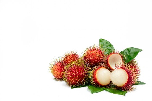 Primo piano del rambutan maturo rosso fresco (Nephelium lappaceum) con le foglie isolate