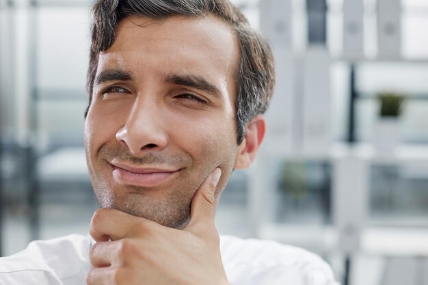 Primo piano del ritratto dell'uomo d'affari concentrato serio che porta camicia bianca che guarda l'obbiettivo