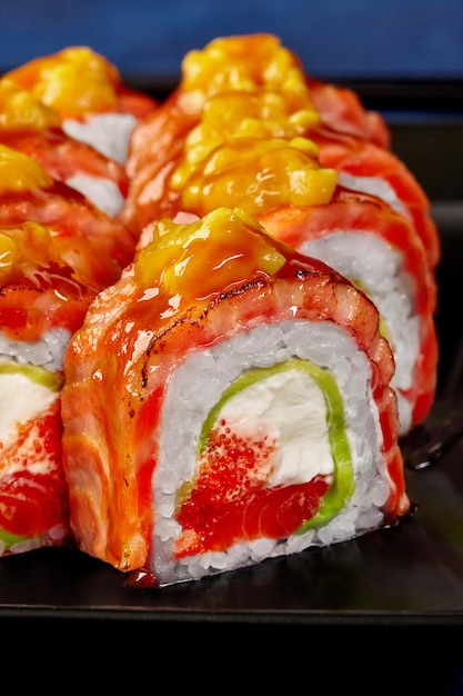 Primo piano del rotolo di uramaki con salmone scottato e mango di avocado tobiko di formaggio cremoso