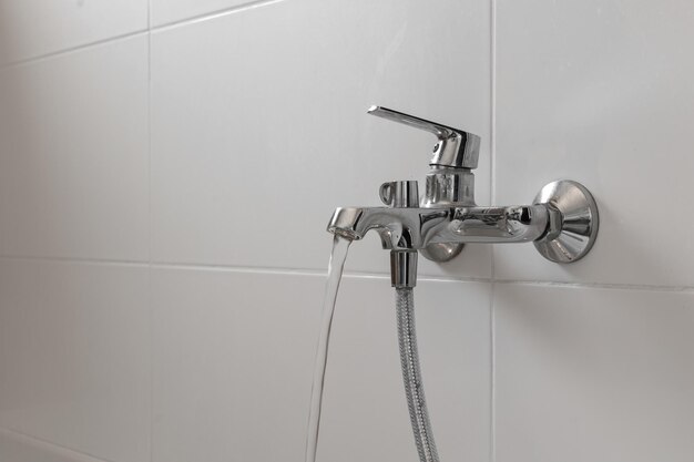 Primo piano del rubinetto cromato e della doccia su un ile bianco in bagno Design del layout del bagno