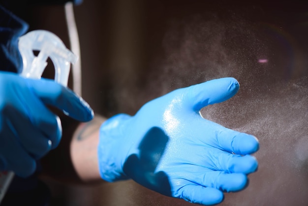 Primo piano del salone del tatuaggio. Un uomo che indossa guanti protettivi disinfetta le mani prima del lavoro.