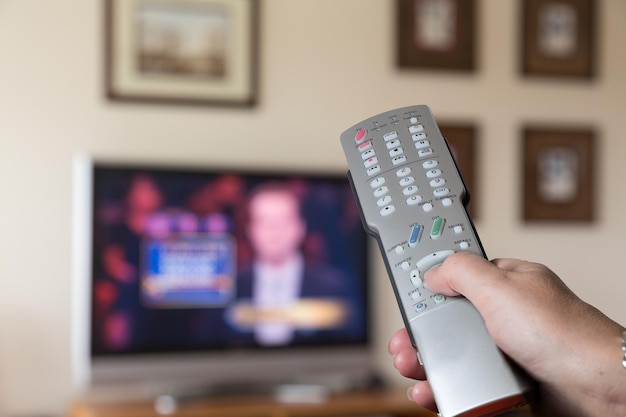 Primo piano del telecomando della TV con la televisione