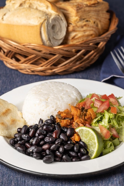 Primo piano del tipico piatto costaricano Casado con riso e fagioli sulla tovaglia blu