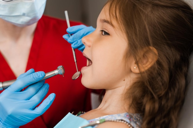 Primo piano del trapano dentale Dentista bambino che perfora i denti della ragazza del bambino nella clinica di odontoiatria Trattamento dei denti Otturazione dentale per il paziente bambino