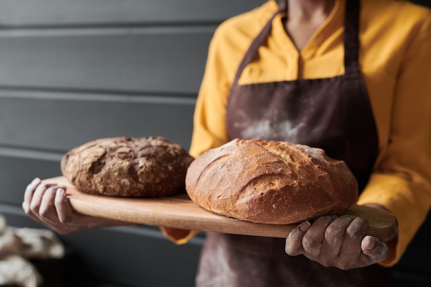 Primo piano del vassoio che tiene il panettiere con pane fresco fatto in casa