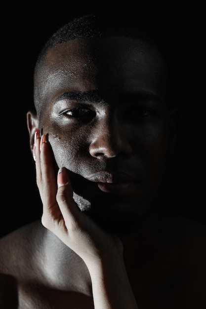 primo piano del viso di un uomo afroamericano con la mano di una donna caucasica sulla guancia luce a 90 gradi