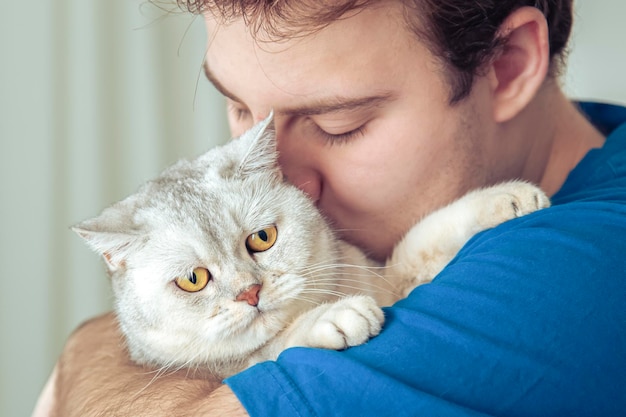 Primo piano del volto di un uomo che tiene il suo simpatico gatto britannico che fa le fusa