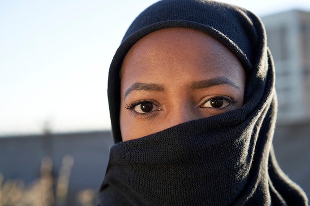 Primo piano del volto di una giovane ragazza musulmana con hijab guardando la telecamera.