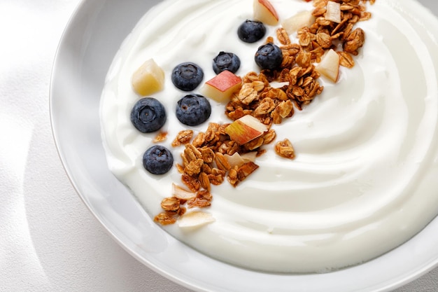 Primo piano Deliziosa ciotola per la colazione sana con mirtilli yogurt con muesli o muesli Vista dall'alto