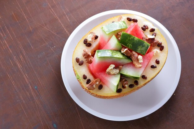 Primo piano delizioso e sano di anguria e melone Fette mature di anguria e melone su un piatto bianco su sfondo scuro