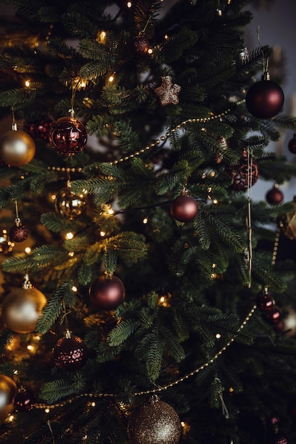 Primo piano dell'albero di Natale splendidamente decorato Luci allegre di ghirlande su un albero di Natale in una stanza buia