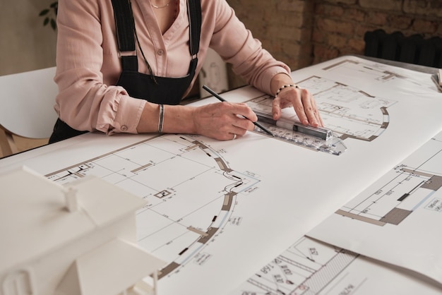 Primo piano dell'architetto femminile irriconoscibile seduto alla scrivania e la creazione di design per un nuovo progetto di costruzione