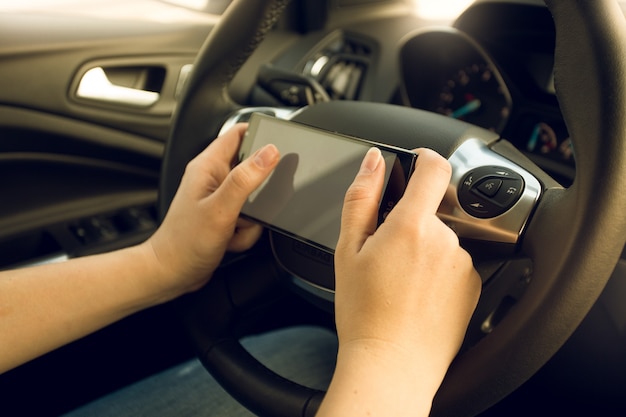 Primo piano dell'autista donna che utilizza lo smartphone durante la guida dell'auto