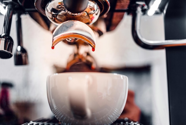 Primo piano dell'estrazione della goccia di caffè dalla macchina da caffè con un portafiltro che versa il caffè