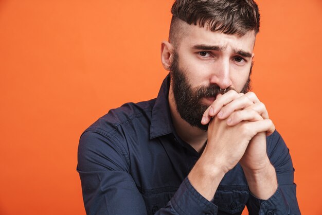 Primo piano dell'immagine di un uomo teso con gioielli al naso che indossa una camicia nera che pensa con i pugni chiusi