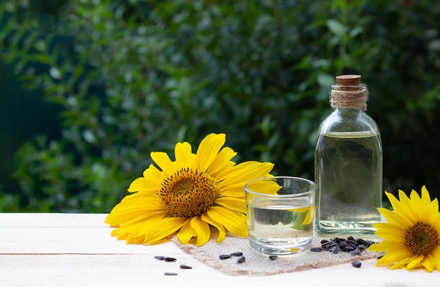 Primo piano dell'olio di girasole in una bottiglia di vetro con semi e girasole