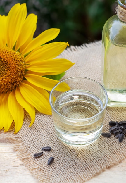 Primo piano dell'olio di girasole in una bottiglia di vetro con semi e girasole