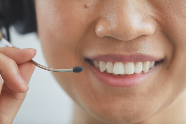 Primo piano dell'operatore che indossa le cuffie sorridendo e parlando al telefono