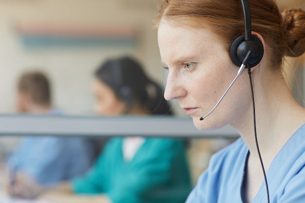 Primo piano dell'operatore femminile in cuffie che si concentra sul suo lavoro nel call center