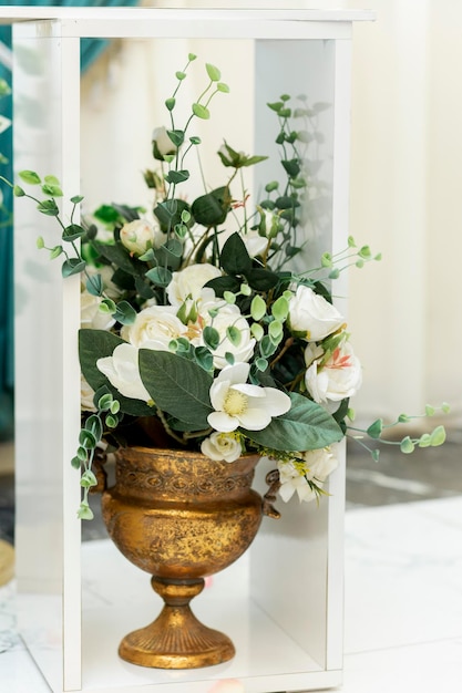 Primo piano dell'ornamento di nozze Fiori bianchi artificiali in vaso di metallo sul pavimento nella sala banchetti