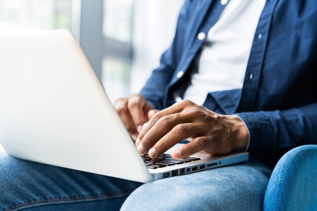 Primo piano dell'uomo africano che scrive sul computer portatile.