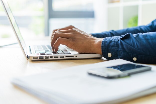 Primo piano dell'uomo africano che scrive sul computer portatile.