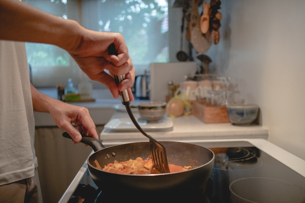 Primo piano dell'uomo che cucina la salsa di pasta in cucina