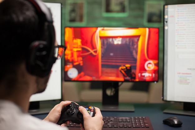 Primo piano dell'uomo che utilizza il joystick durante la riproduzione di giochi sparatutto su un computer potente.