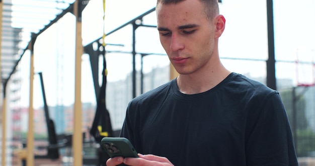 Primo piano dell'uomo che utilizza lo smartphone per controllare le applicazioni fitness in piedi presso il campo sportivo Concetto di stile di vita sano