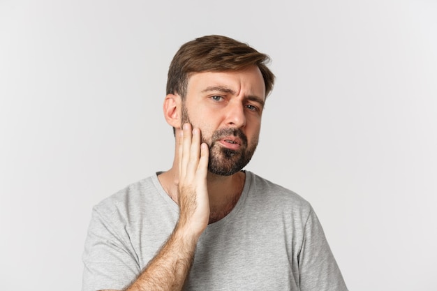 Primo piano dell'uomo confuso che tocca la sua barba e che guarda se stesso