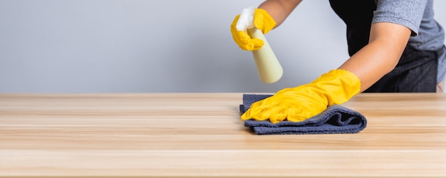Primo piano dell'uomo delle pulizie che lavora in negozio pulito su un tavolo di legno, concetto di coronavirus di protezione