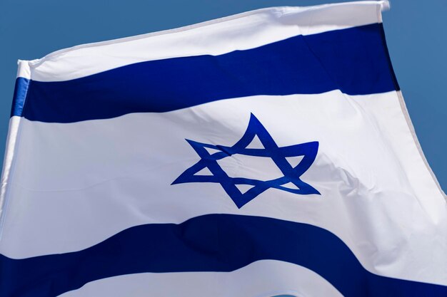 Primo piano della bandiera nazionale israeliana si sviluppa in un'onda nel vento Il concetto di giorno dell'indipendenza di Israele Yom Haatzmaut Bandiera Israele con l'albero che sventola nel vento Simboli nazionali dello stato copiano lo spazio