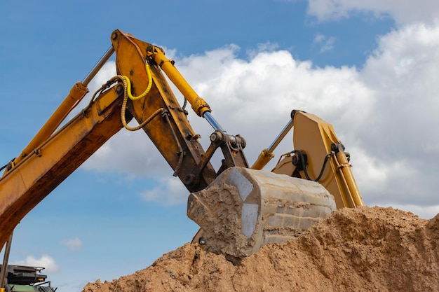 Primo piano della benna dell'escavatore al cielo blu soleggiato del cantiere sullo sfondo Attrezzature da costruzione per lavori di sterro