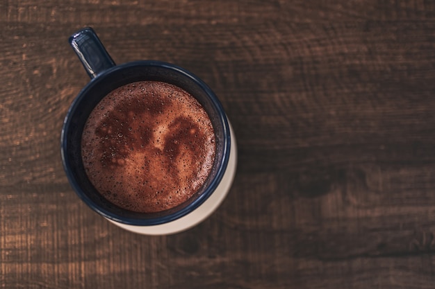 Primo piano della bevanda di cioccolata calda in tazza blu su tavola di legno