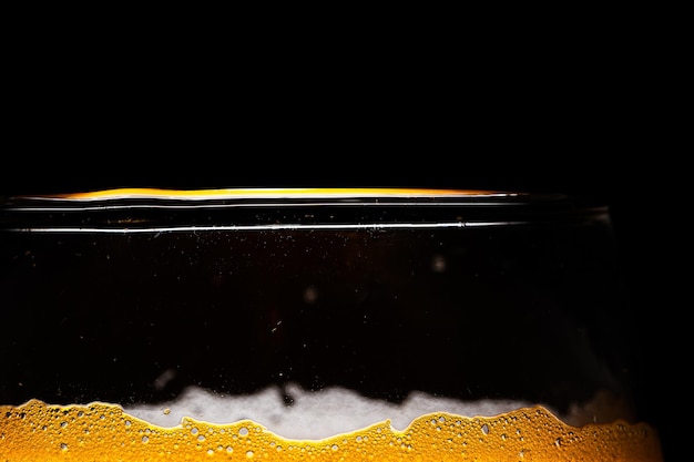 Primo piano della birra Primo piano in schiuma e bolle di birra su sfondo nero. Sfondo di gocce d'acqua