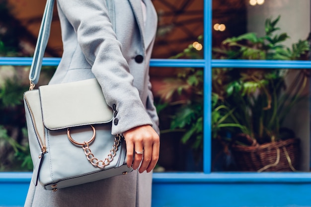 Primo piano della borsa femminile blu. Borsa di cuoio della tenuta della donna all'aperto. Accessori e vestiti alla moda