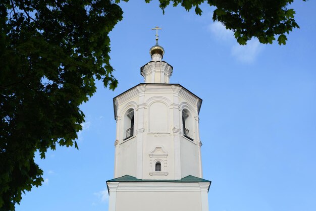 Primo piano della chiesa bianca con croce contro il cielo blu un antico monastero in cornice di alberi all'aperto