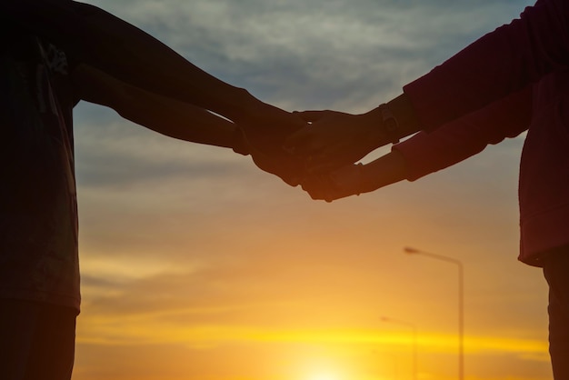 Primo piano della coppia di innamorati che si tiene per mano mentre si cammina al tramonto