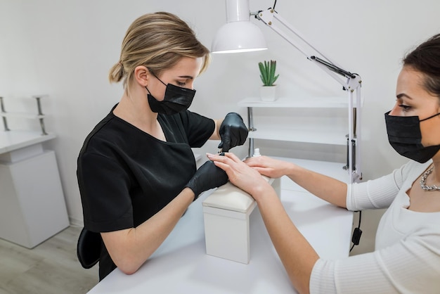 Primo piano della cura delle unghie delle dita da parte di uno specialista di manicure nel salone di bellezza Tronchese professionale per cuticole trasparenti per manicure e pedicure