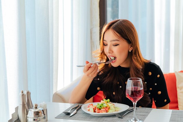 Primo piano della donna asiatica che mangia insalata di verdure fresche