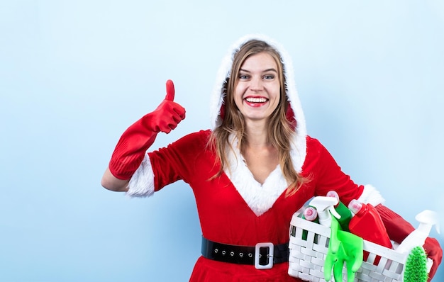 Primo piano della donna caucasica felice che indossa abiti da Babbo Natale e guanti per la pulizia che tengono spray per la pulizia