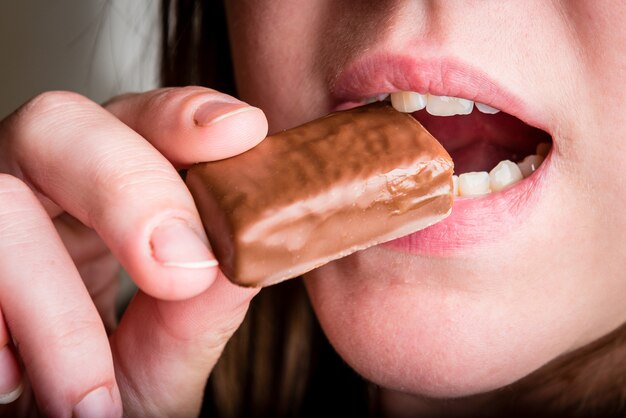 Primo piano della donna che mangia dolce al cioccolato.