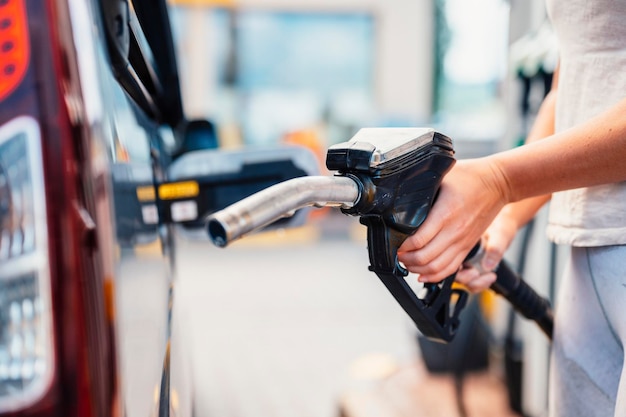 Primo piano della donna che pompa carburante a benzina in auto alla stazione di servizio Benzina o benzina pompata in un motore Concetto di trasporto