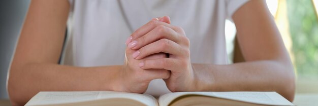 Primo piano della donna che si siede al tavolo e che mette le mani in serratura sul lettore o sull'avvocato femminile del grande libro