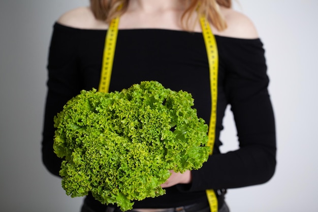 Primo piano della donna che tiene i broccoli con nastro adesivo per misurare.