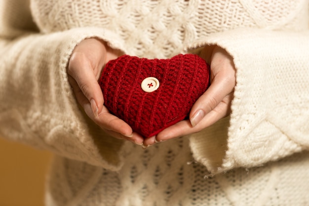 Primo piano della donna che tiene il cuore rosso nelle mani