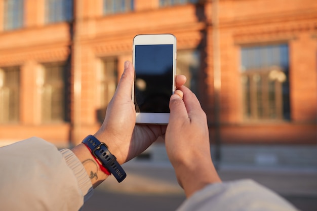 Primo piano della donna che tiene il telefono cellulare e che fotografa l'edificio all'aperto in città