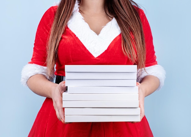 Primo piano della donna felice caucasica che indossa abiti da Babbo Natale che tiene un mucchio di libri in bianco